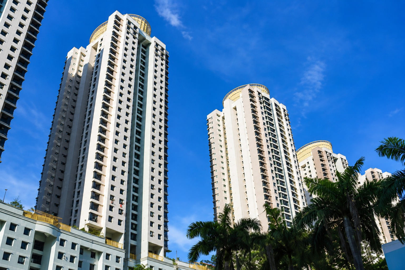 Tall older Singapore condominium blocks under a blue sky, the kind of ageing private developments affected by the new en bloc thresholds